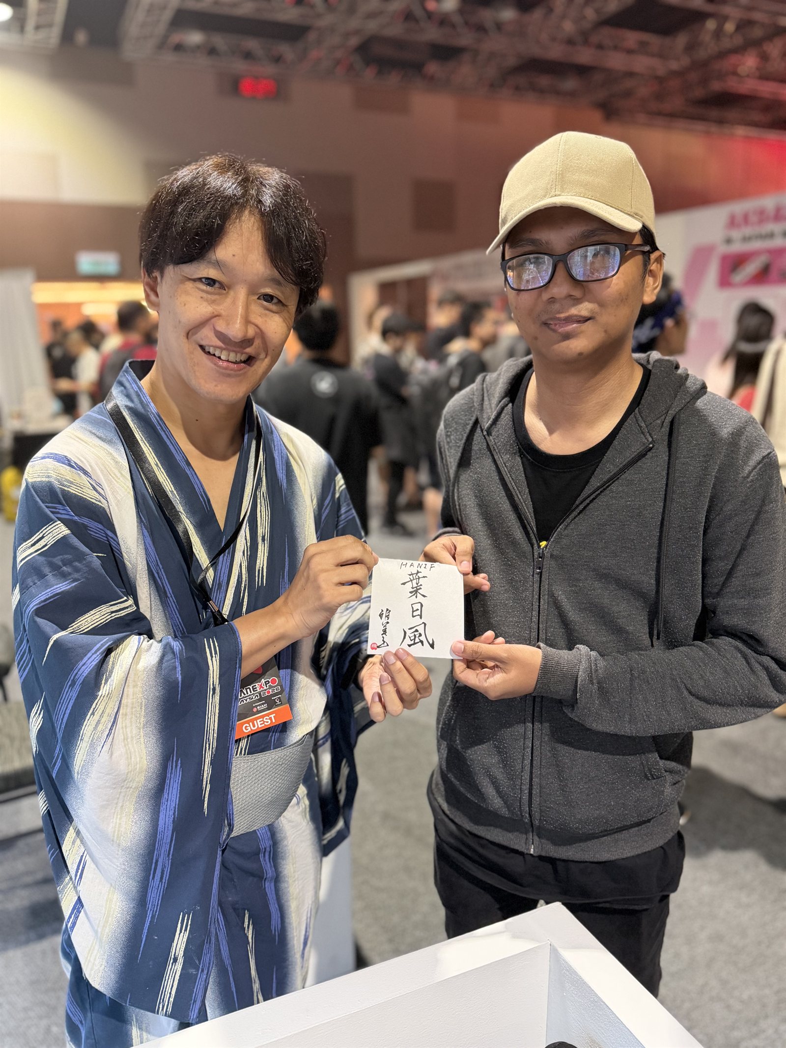 来場者の名前を漢字で揮毫した色紙を手渡す荻沼雅美 ─ JAPAN EXPO MALAYSIA 2026