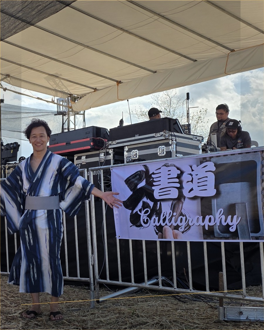 セブ盆踊り2026の書道バナーの前に立つ荻沼雅美