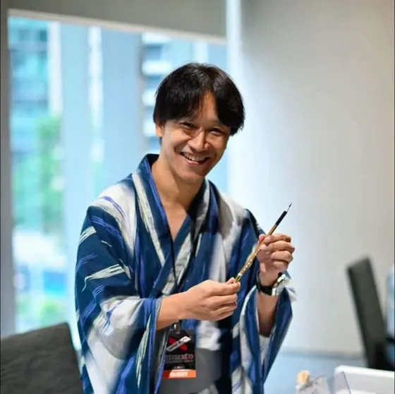 筆を構えて微笑む荻沼雅美